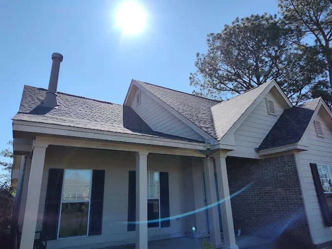 Suburban house with white siding, brick accent, and black shutters on sunny day